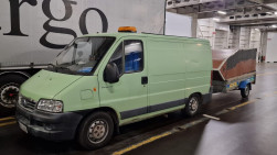Pakettiauto ja perävaunu autolautan sisällä.