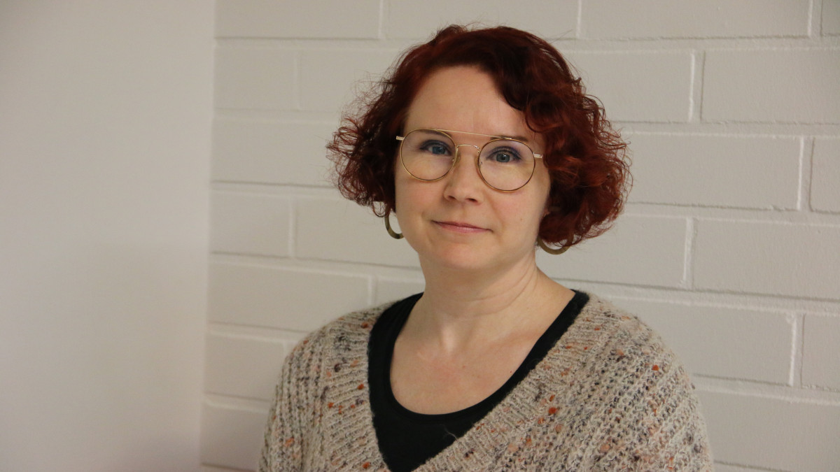 Taina Leskinen istuu ja katsoo kameraan.