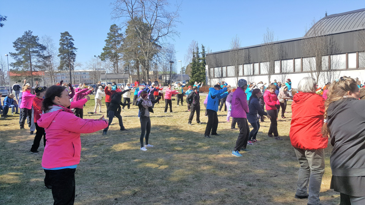 Ihmisiä jumppamassa urheilutalo-uimahallin pihalla.