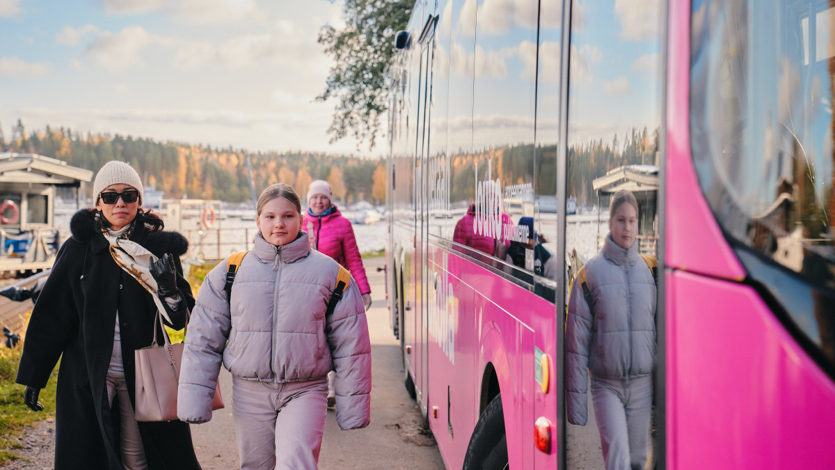 Matkustajia linja-auton vieressä.