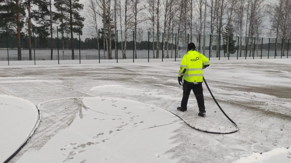 Kiinteistöpalvelun työntekijä jäädyttää ulkokenttää.