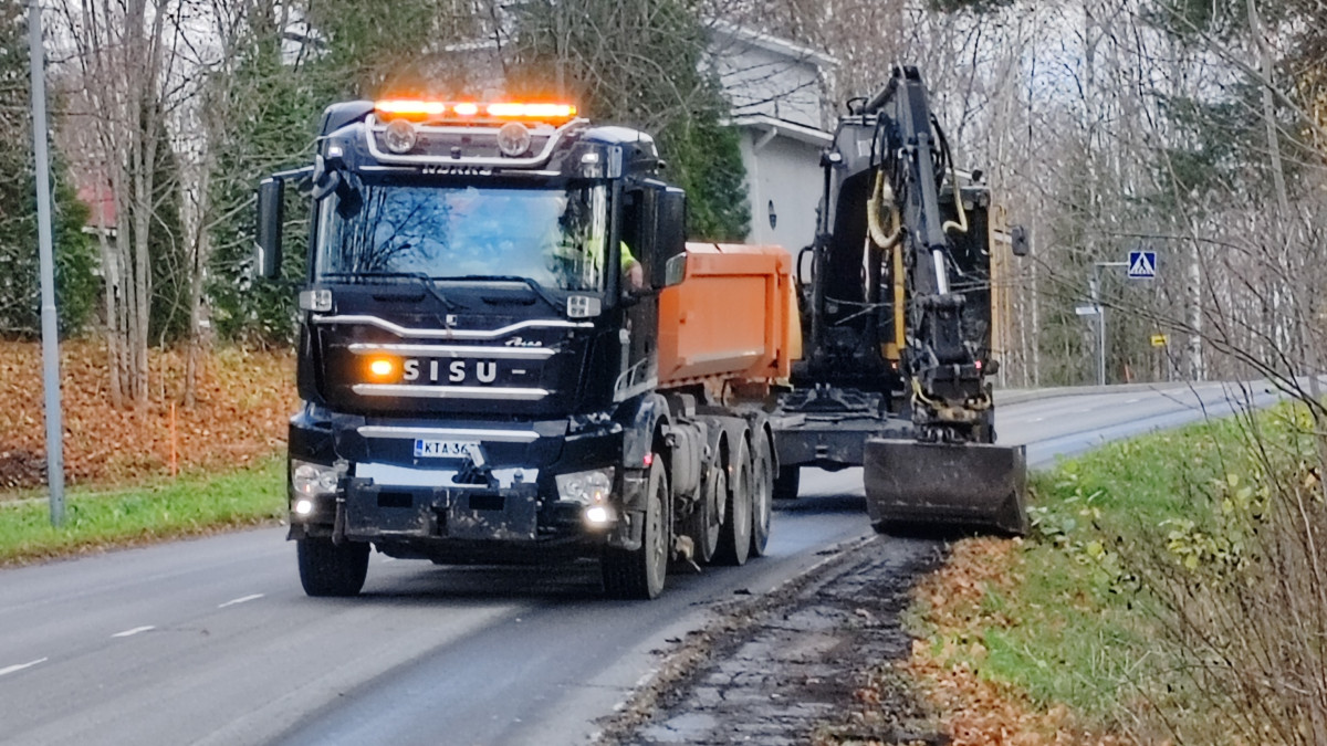 Kuorma-auto ja kaivinkone poistamassa tien reunapalteita.
