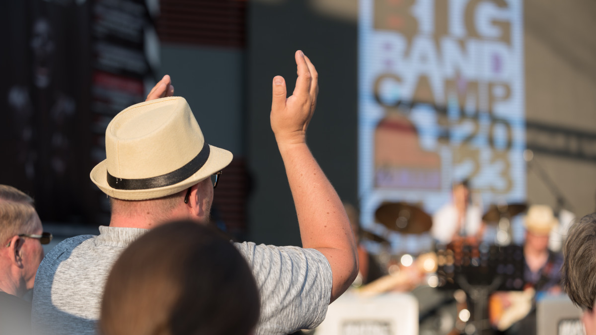 Yleisöä lavan edessä selkäpäin kameraan. Lavan näytössä teksti: Imatra Big Band Camp 2023.