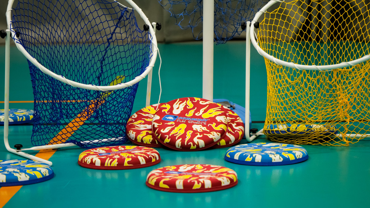 Isoja, eri värisiä frisbeekiekkoja ja korit liikuntahallin lattialla.