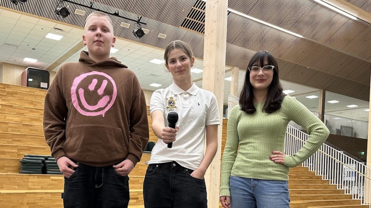 Kolme nuorta seisomassa suuren portaikon edessä.
