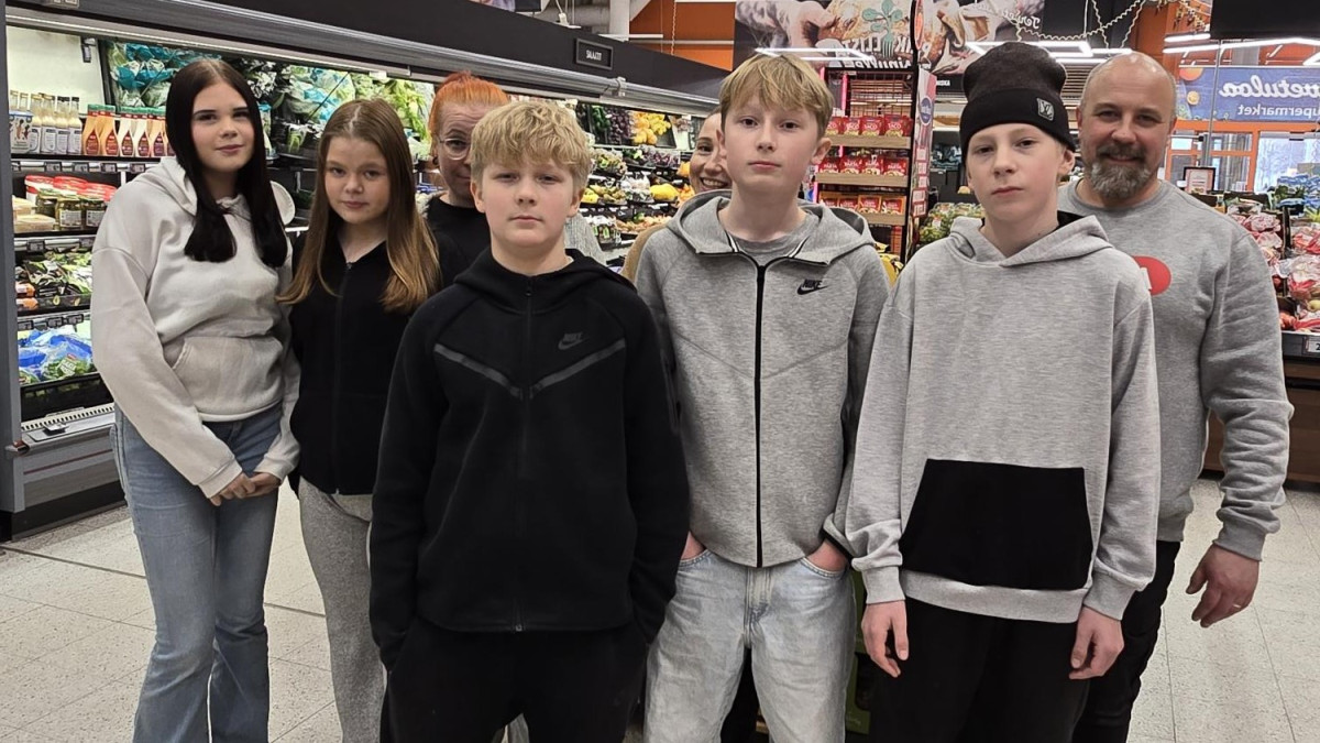 Oppilaita ja aikuisia kaupassa.