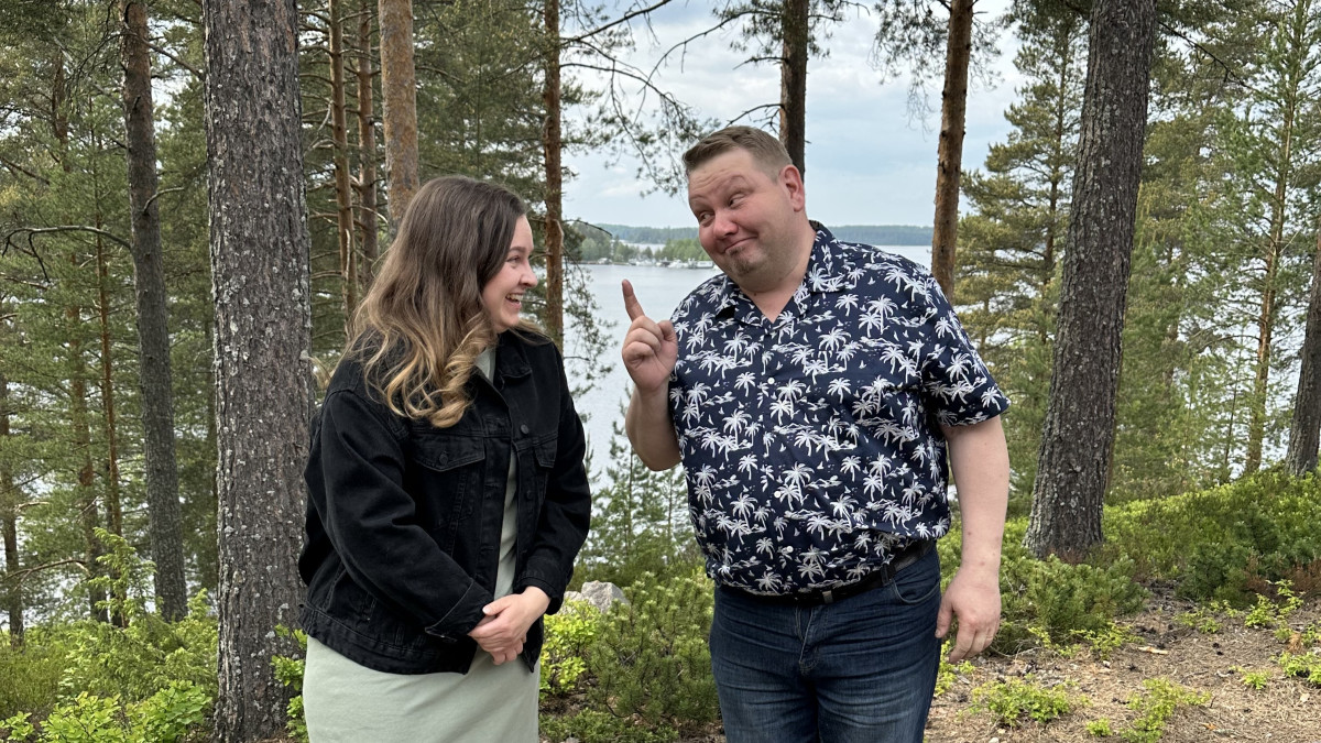 Mies ja nainen keskustelevat järvimaiseman edessä.