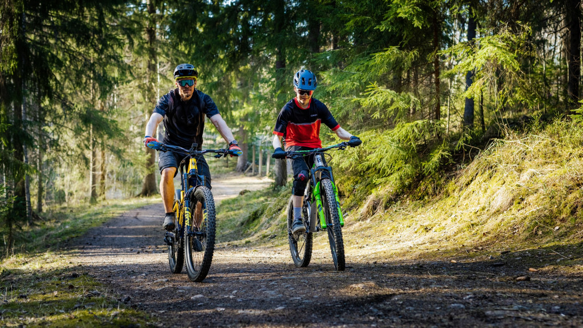 Kaksi maastopyöräilijää metsäpolulla.