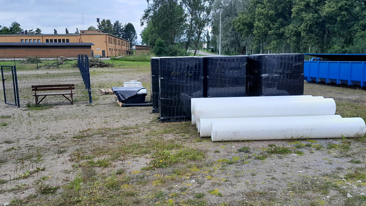 Viemäreiden valkoisia sujutusputkia maassa hiekkakentällä.