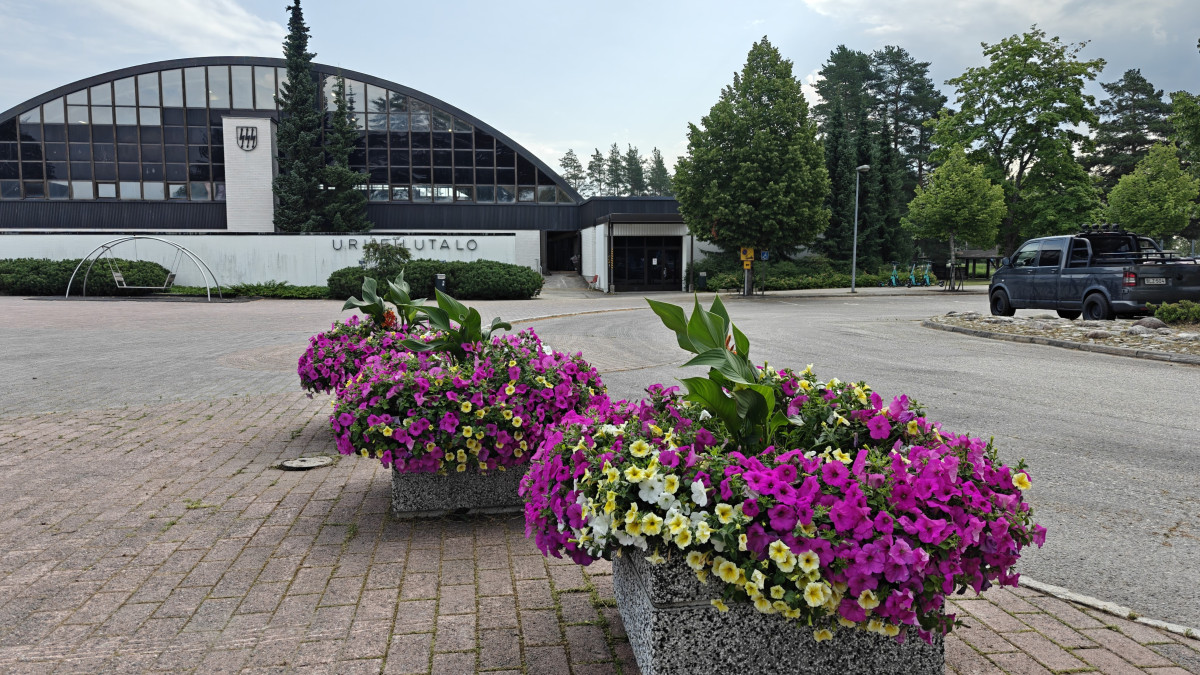 Urheilutalo ulkoapäin, etualalla kukkaistutuksia.