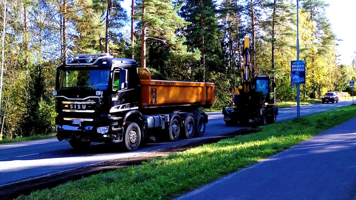 Kuorma-auto ja kaivinkone poistamassa tien reunapalteita.