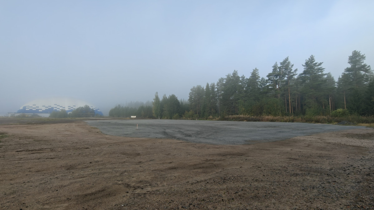 Hiekka-alue, taustalla näkyy kuplahalli ja metsää.