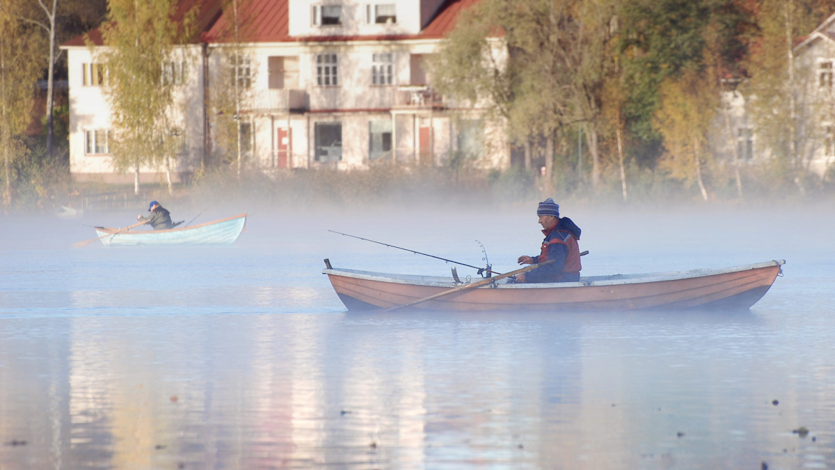 Soutuveneilijä sumuisella järvellä.