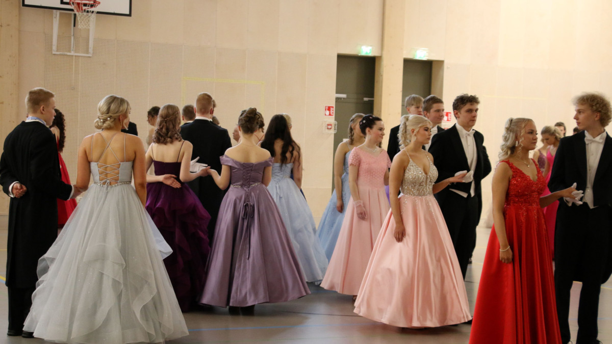 Vanhojentanssipareja ympyrämuodostelmassa, jonossa liikuntasalissa.