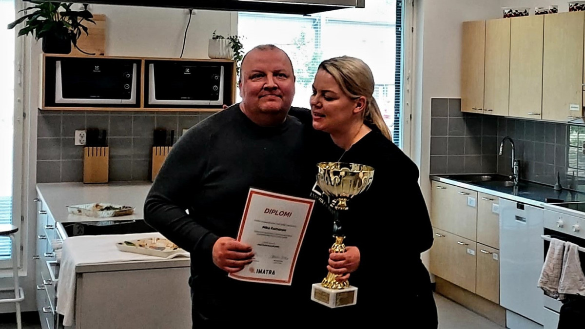 Mika Korhonen kädessään Arjen tekijä-diplomi saa halauksen ja pokaalin rehtori Johanna Ovaskalta.