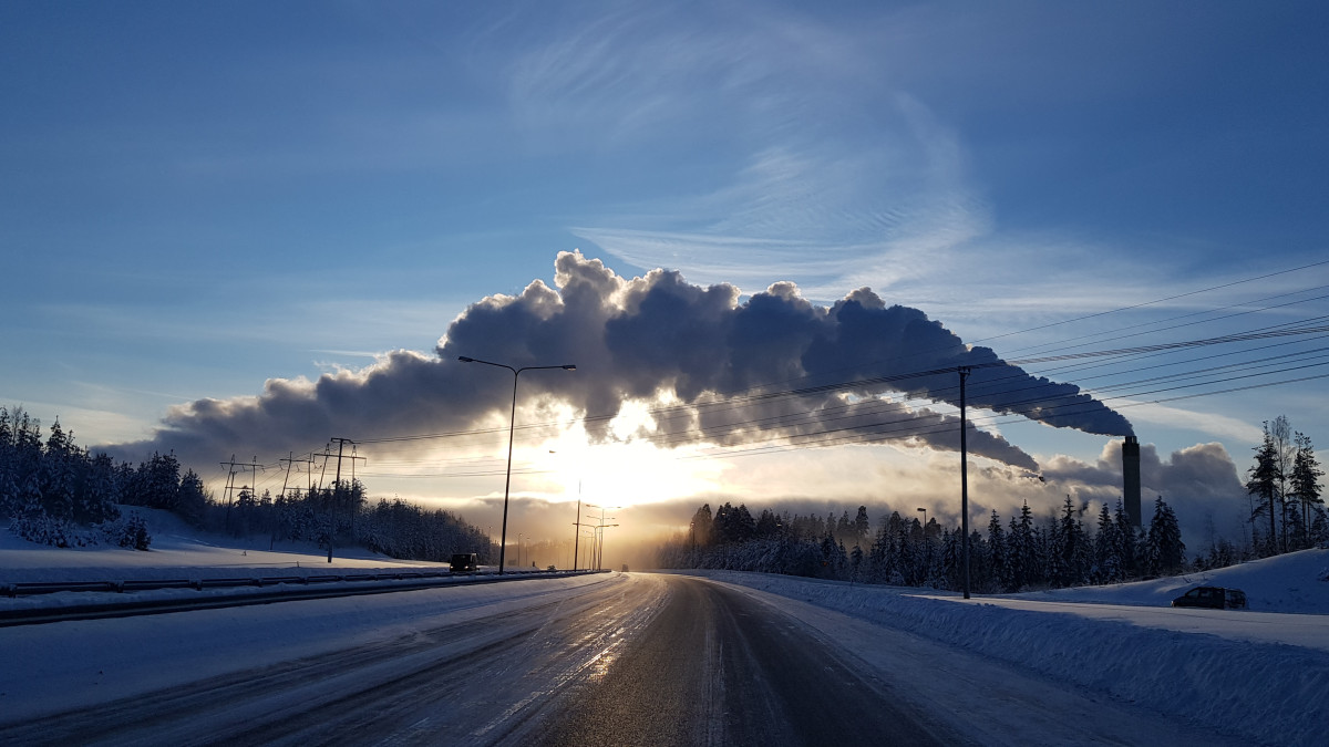 Tehtaan savut taivaalla auringon laskiessa.