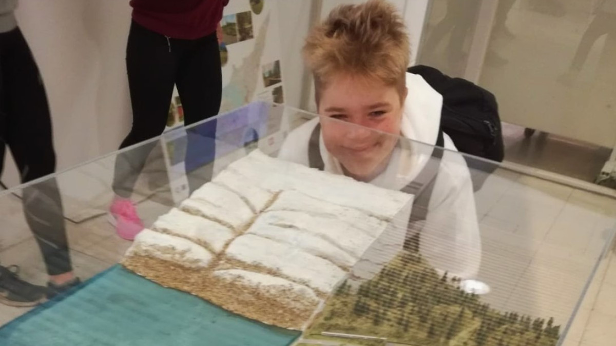 Opiskelija katsoo vitriinissä olevaa jääkausimaisemaa.