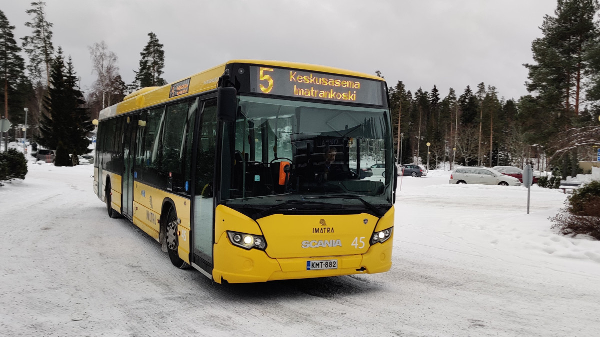 linja-auto edestä, taustalla parkkipaikka ja kuusia.
