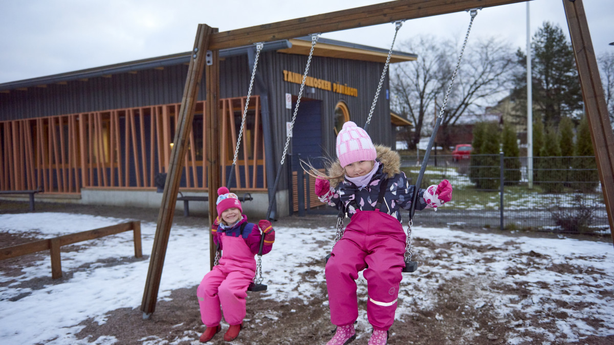 Lapsia keinumassa päiväkodin pihalla.