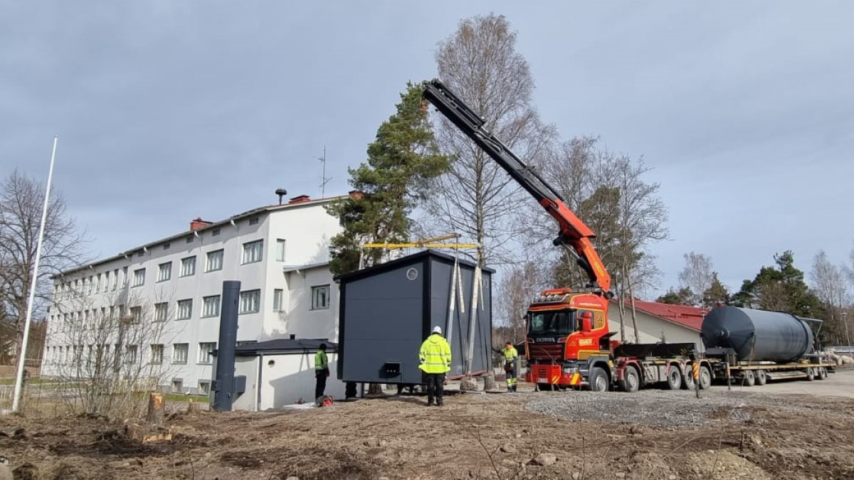 koulurakennus, kontti ja nosturi.