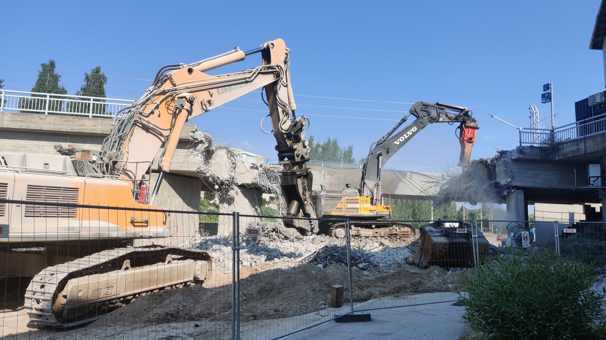 kaksi kaivinkonetta purkamassa siltaa.