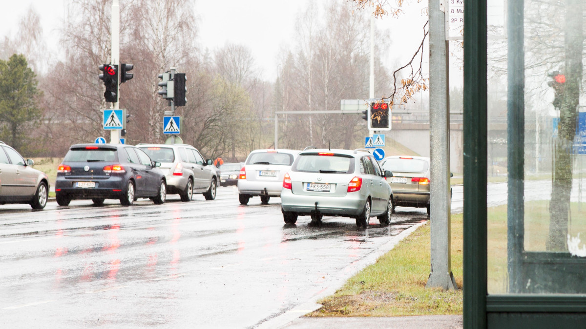 Autoja liikennevaloissa, etualalla bussipysäkki.