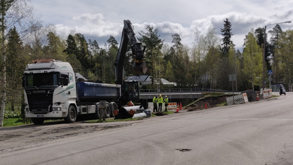 Kuorma-auto ja työmiehiä kaivuutöissä ajotien reunassa.