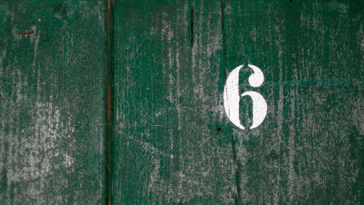 Numero kuusi puisella seinällä.