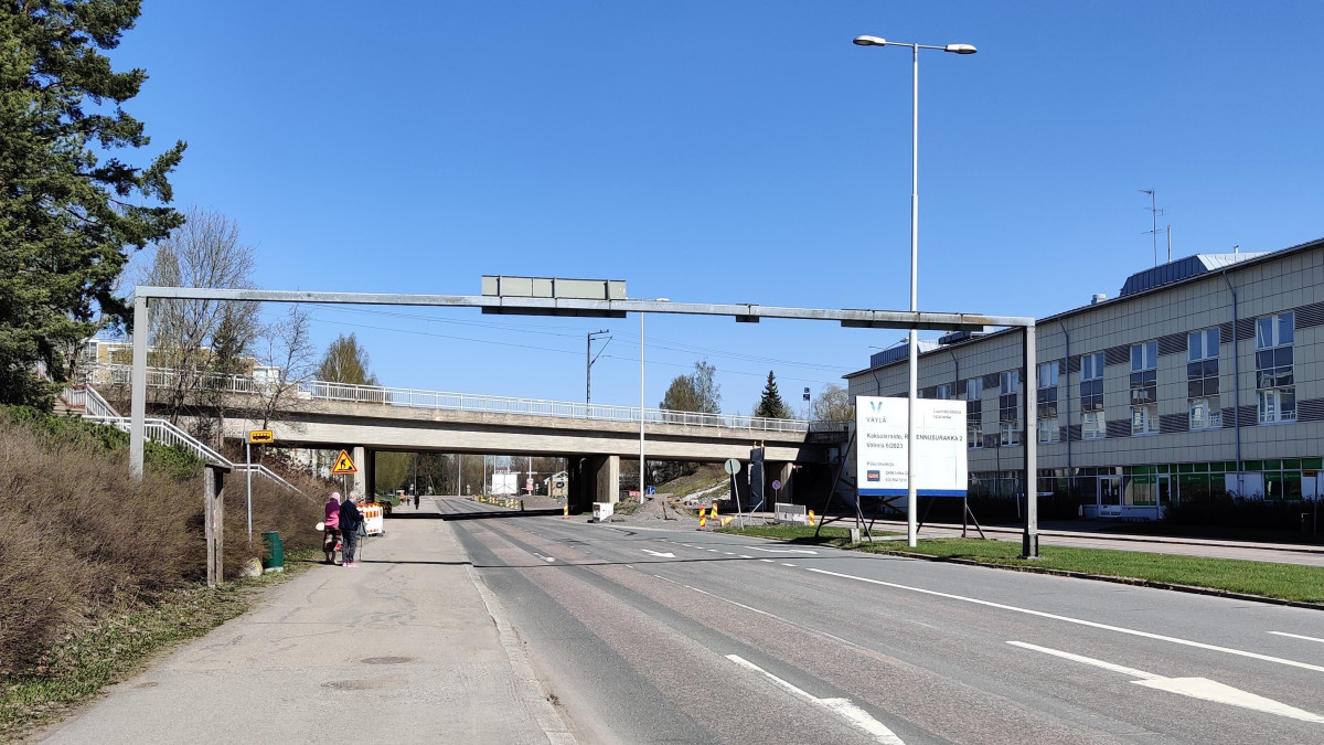 tiettä, silta ja kaksi ihmistä bussipysäkillä.