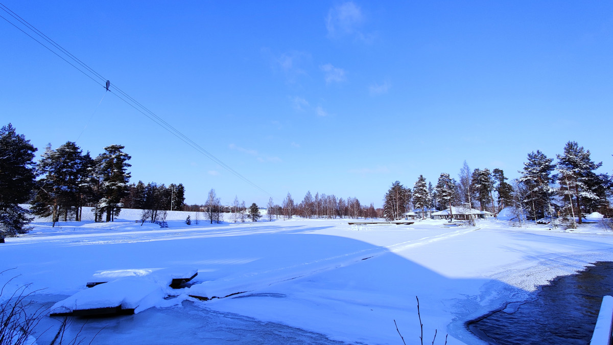 Talvinen kuva Vuokselta. Kuvassa saari, aurinko paistaa.