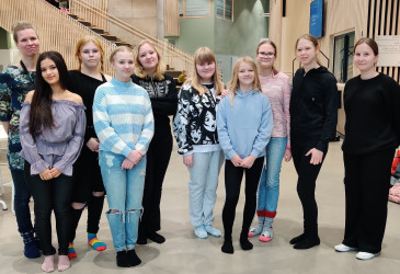 Oppilaat rivissä koulun ruokala taustanaan.