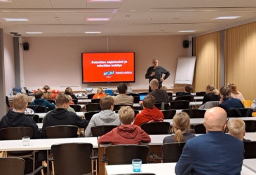 Seminaari, jossa oppilaat istumassa selin kameraan.