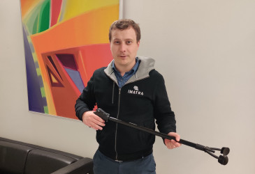Mies roskapihdit kädessä, taideteos taustalla.