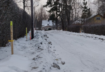Talvinen näkymä kadulta, jonka reunoilla pensasaitaa ja pari omakotitaloa.