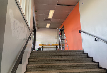 Aseman sisäpintojen maalaustyöt ovat käynnissä. KUvassa oranssin seinän maalaus.