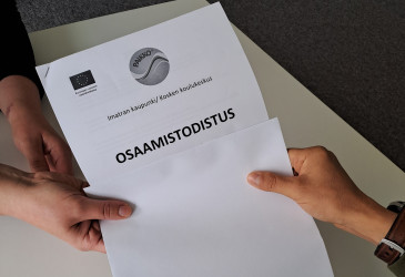 Kaksi kättä pitää kiinni osaamistodistuksesta.