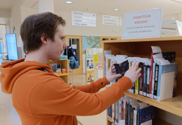 Mies tutkii varattuja kirjoja.