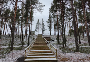 Kuntoportaat nousevat rinteellä, jossa ohut lumikerros harmaana päivänä.