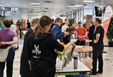 Urheilutalon aulassa tapahtuman yleisöä ja esittelijöitä.