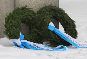 Kaksi seppelettä muistomerkin juuressa.
