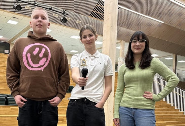 Kolme nuorta seisomassa suuren portaikon edessä.