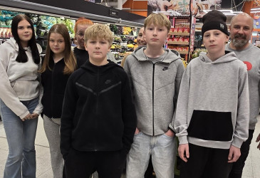 Oppilaita ja aikuisia kaupassa.