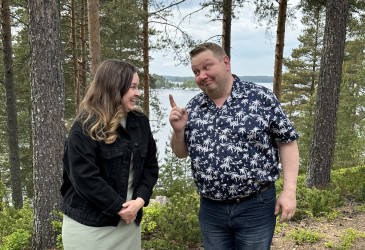 Mies ja nainen keskustelevat järvimaiseman edessä.