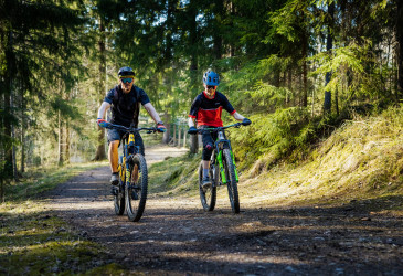 Kaksi maastopyöräilijää metsäpolulla.