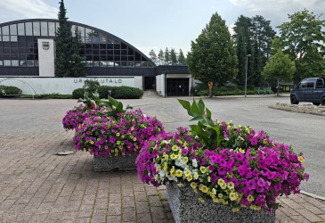 Urheilutalo ulkoapäin, etualalla kukkaistutuksia.