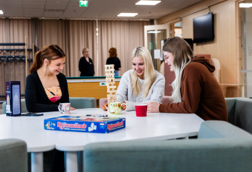 Kolme nuorta istuu pöydän ääressä ja pelaavat Huojuva torni -peliä.