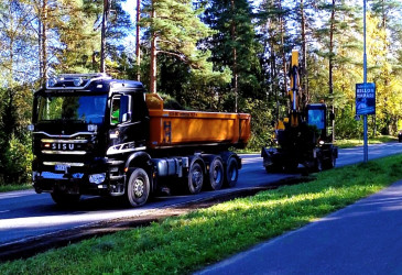Kuorma-auto ja kaivinkone poistamassa tien reunapalteita.