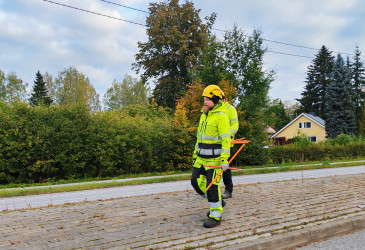Työntekijä asentaa aurausviittoja kadulla.