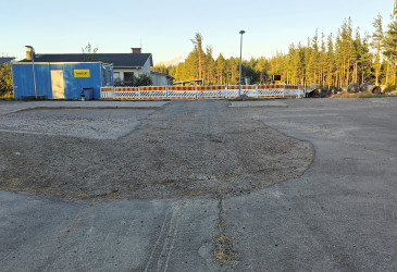 Paikoitusalueen asfaltissa korjattava alue, taustalla työmaa-aita ja -koppi.