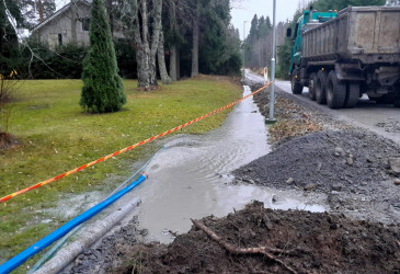 Asuinkadun ojassa paljon vettä, kuorma-auto ojan vieressä tiellä.
